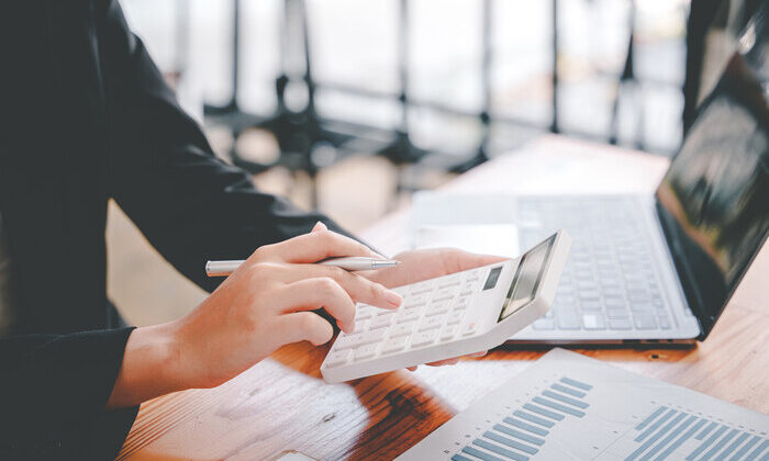 business woman or accountant who are using a calculator to calculate business data Accounting documents and laptop computer at the office business idea