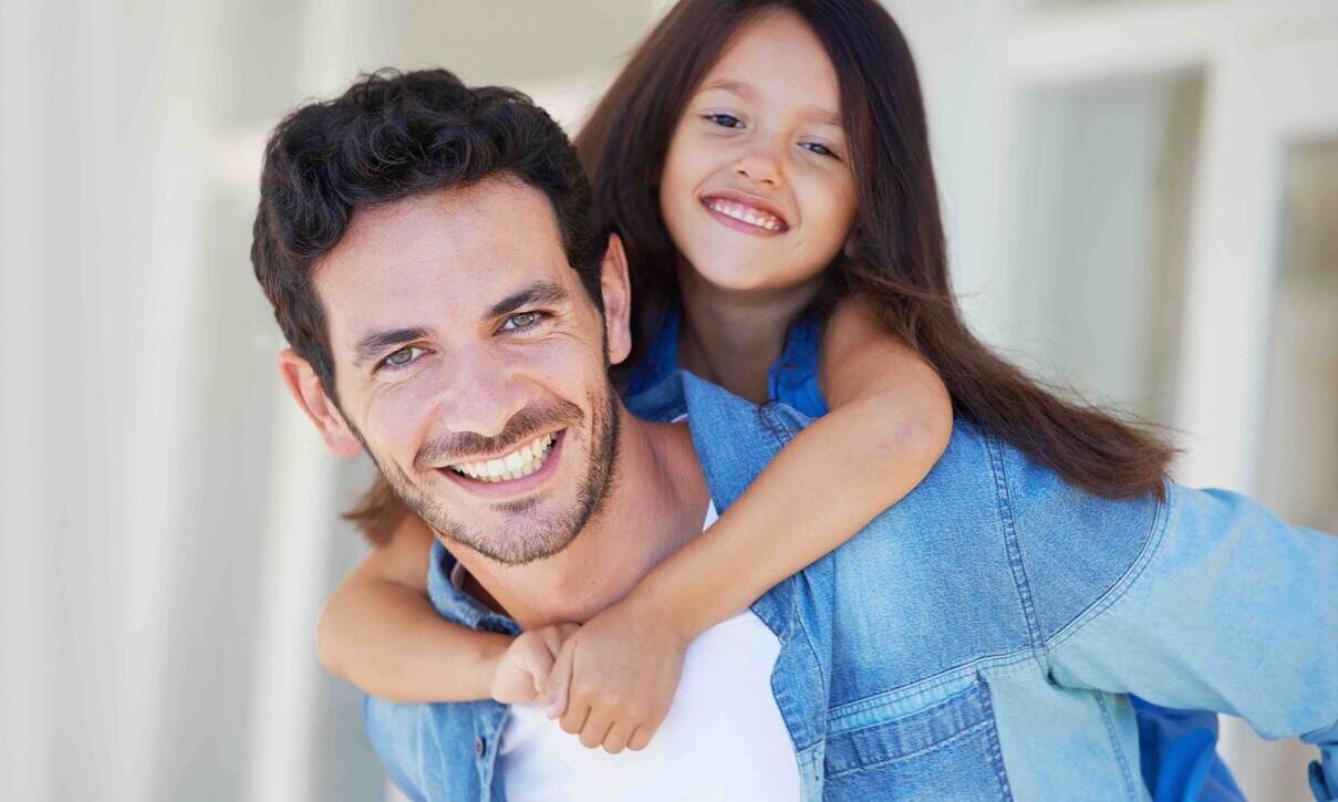 Portrait of a smiling little girl getting a piggyback from her father