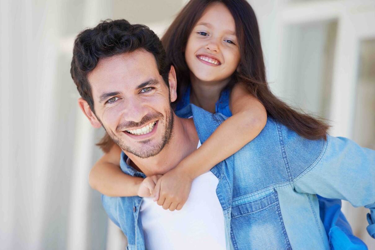 Portrait of a smiling little girl getting a piggyback from her father