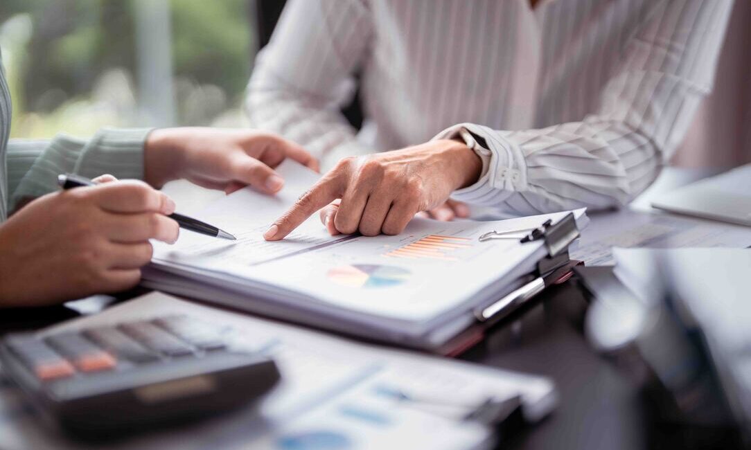 Budget 2026 Key Announcements - Two colleagues work together on a document, referencing a calculator for numerical data.