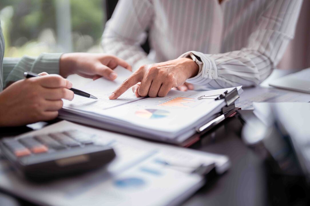 Budget 2026 Key Announcements - Two colleagues work together on a document, referencing a calculator for numerical data.