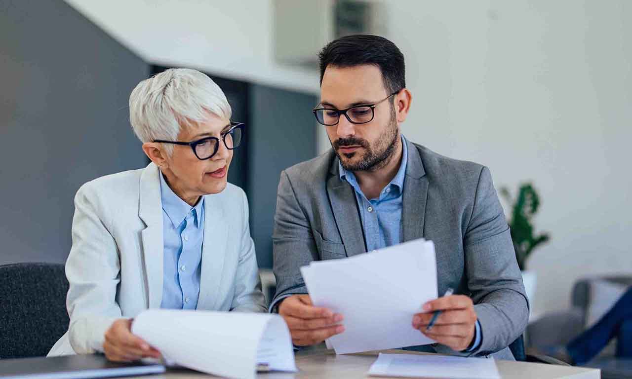Defined Contribution Pension - A man and woman are reviewing paperwork together at a table, focused on the documents in front of them.