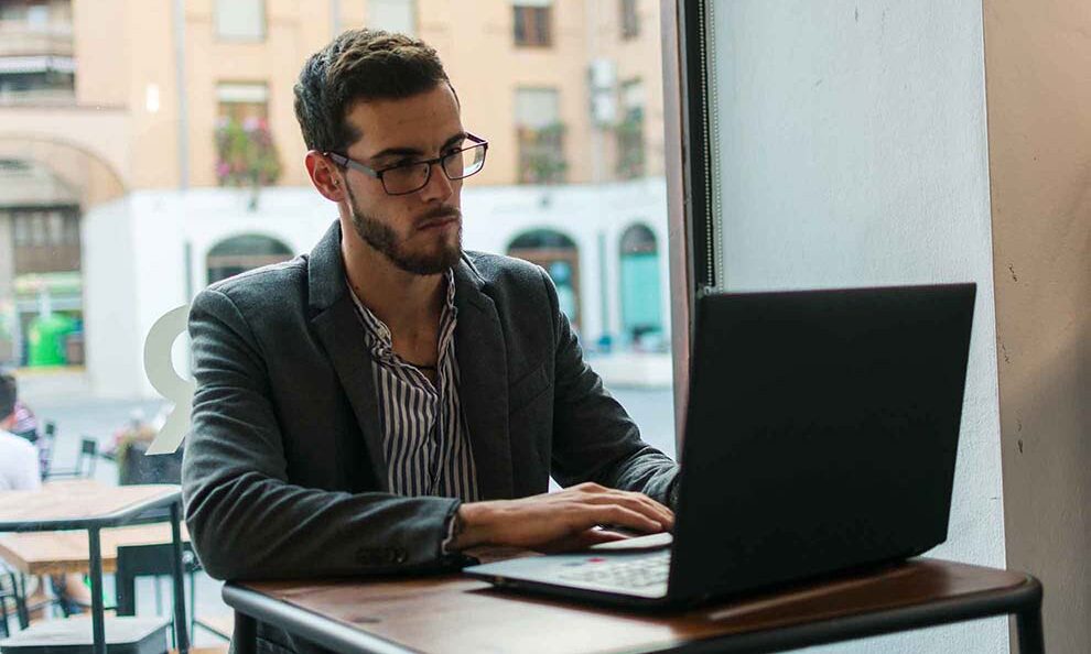 Early Retirement in Ireland - A man wearing glasses is focused on working on his laptop at a desk.