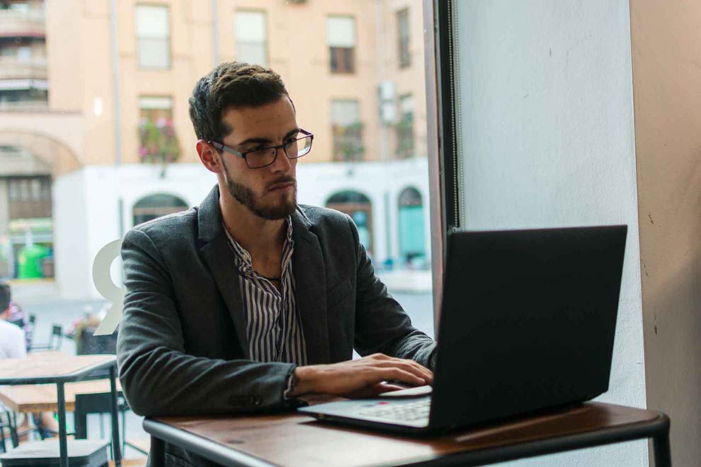 Early Retirement in Ireland - A man wearing glasses is focused on working on his laptop at a desk.